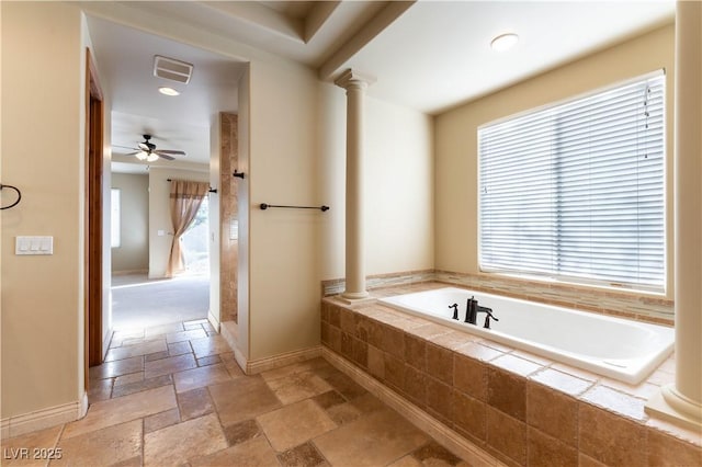 bathroom featuring ceiling fan, tiled tub, and decorative columns