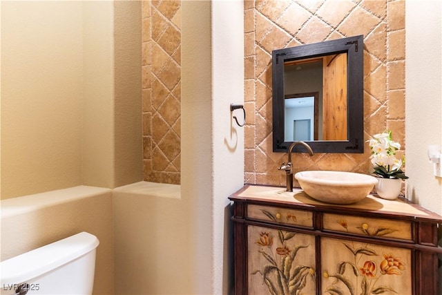 bathroom with toilet, vanity, and decorative backsplash