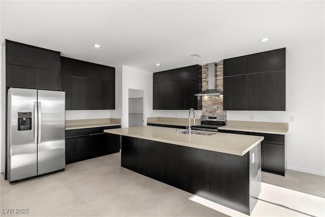 kitchen featuring stainless steel appliances, wall chimney range hood, sink, and a kitchen island with sink