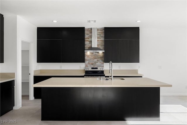 kitchen with a center island with sink, electric stove, wall chimney range hood, and sink