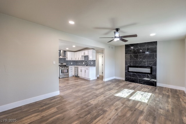 unfurnished living room with sink, a fireplace, ceiling fan, and hardwood / wood-style flooring