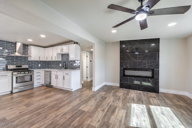 kitchen with stainless steel appliances, white cabinets, and wall chimney exhaust hood