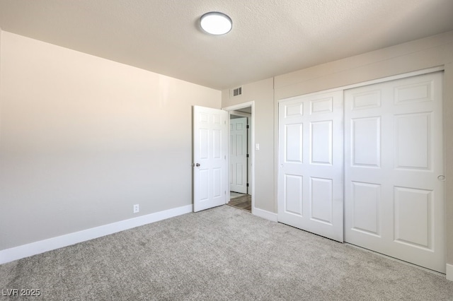 unfurnished bedroom with a closet, light carpet, and a textured ceiling