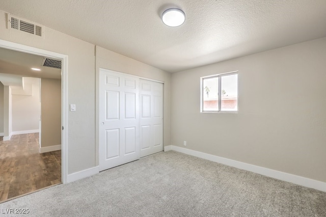 unfurnished bedroom with a textured ceiling, a closet, vaulted ceiling, and carpet flooring