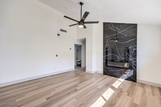 living room with a textured ceiling, ceiling fan, light wood-type flooring, and vaulted ceiling