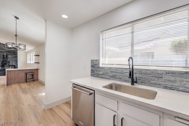 kitchen with sink, white cabinets, dishwasher, light stone counters, and pendant lighting