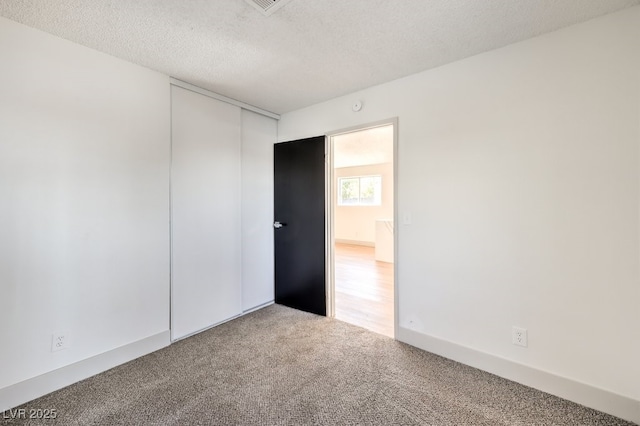 carpeted empty room with a textured ceiling