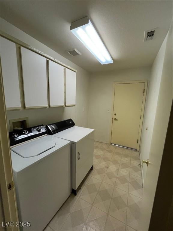 washroom with washer and clothes dryer and cabinets