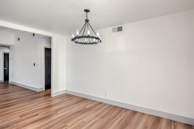 unfurnished room featuring light wood-type flooring and an inviting chandelier