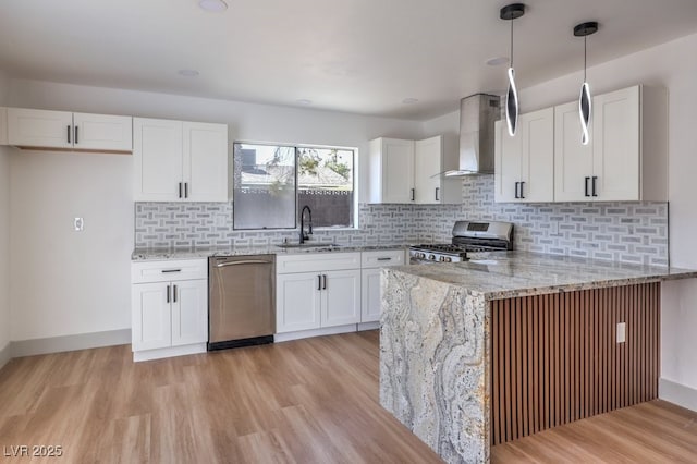 kitchen featuring sink, stainless steel appliances, white cabinetry, and wall chimney range hood