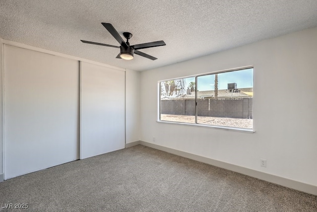 empty room featuring a textured ceiling, ceiling fan, and carpet