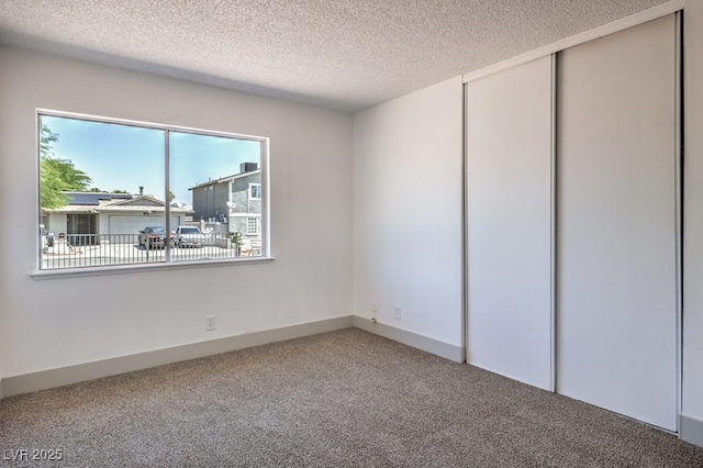 unfurnished room with a textured ceiling and carpet floors