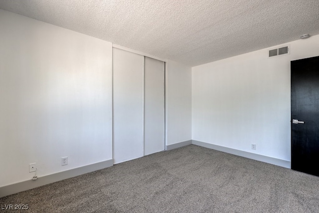 unfurnished room featuring a textured ceiling and carpet flooring