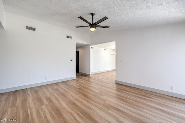 empty room featuring a textured ceiling, ceiling fan, light wood-type flooring, and vaulted ceiling