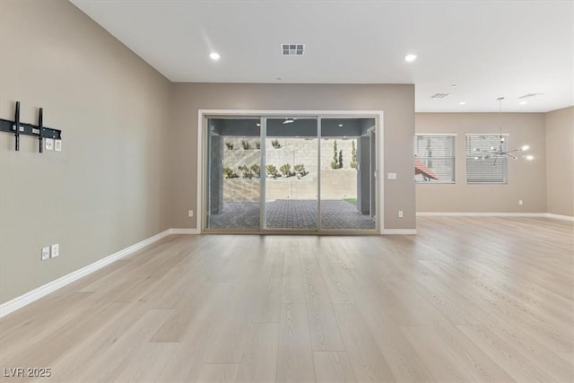 unfurnished room featuring an inviting chandelier and light hardwood / wood-style floors