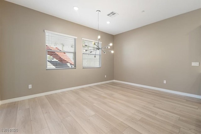 unfurnished room featuring light hardwood / wood-style flooring and a notable chandelier