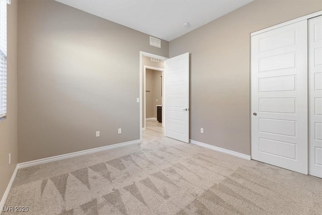 unfurnished bedroom with light colored carpet and a closet