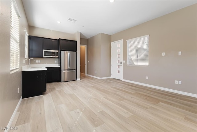 kitchen with stainless steel appliances, light hardwood / wood-style floors, and sink