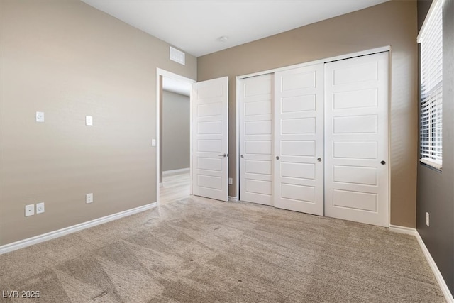 unfurnished bedroom featuring a closet and light carpet