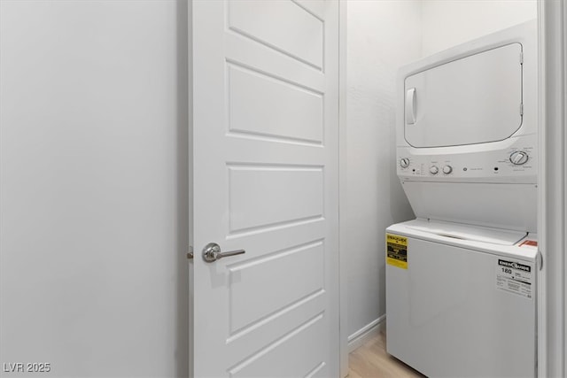 washroom with stacked washer / drying machine and light wood-type flooring