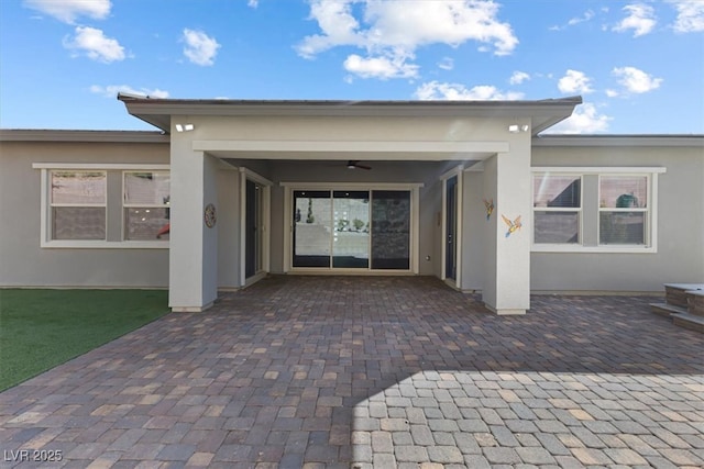 entrance to property with ceiling fan and a patio