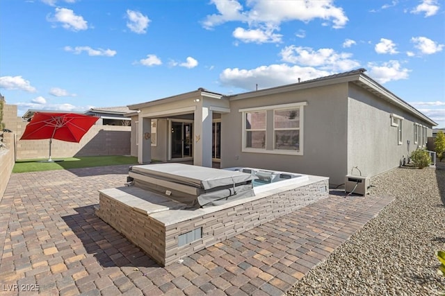 rear view of property with a patio and a covered hot tub