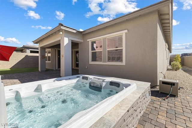 back of property featuring a hot tub and a patio