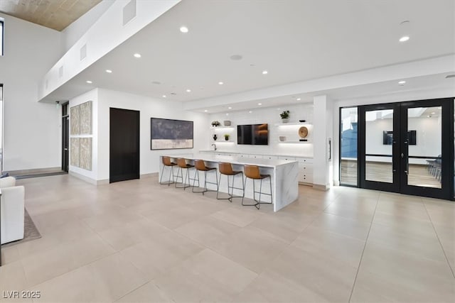 kitchen with white cabinetry, a kitchen breakfast bar, french doors, and a spacious island