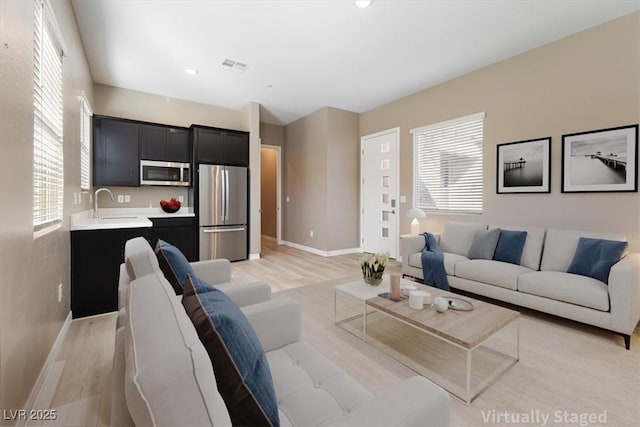 living room with sink, a wealth of natural light, and light hardwood / wood-style flooring