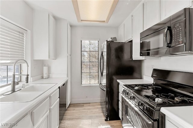 kitchen featuring light hardwood / wood-style flooring, white cabinets, black appliances, and sink