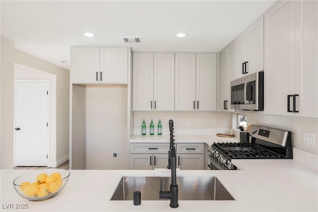 kitchen featuring stainless steel appliances, white cabinets, and sink