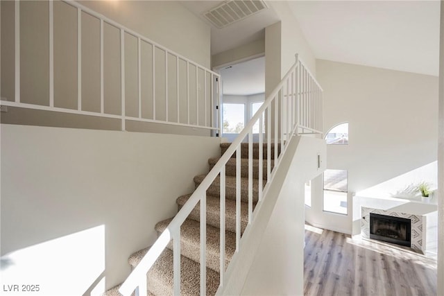 stairway featuring hardwood / wood-style floors and a high end fireplace