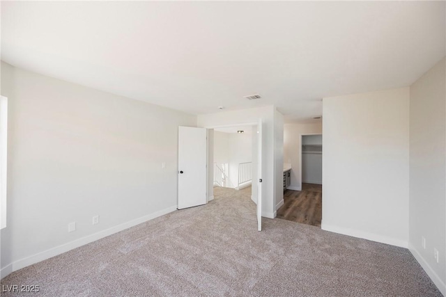 unfurnished bedroom featuring light colored carpet, a spacious closet, and a closet