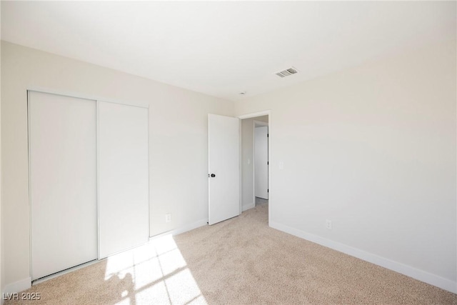 unfurnished bedroom with light colored carpet and a closet