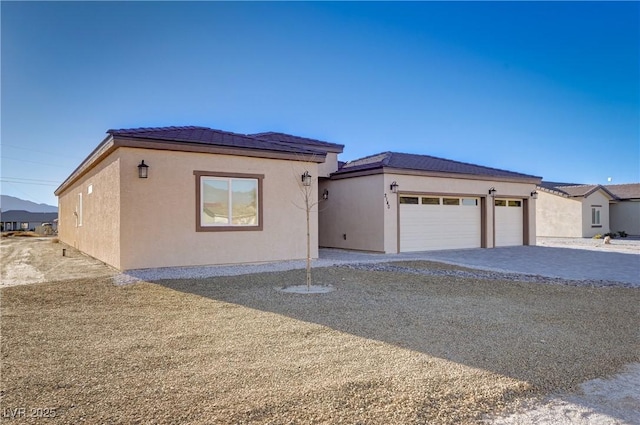 view of front facade with a garage, driveway, and stucco siding