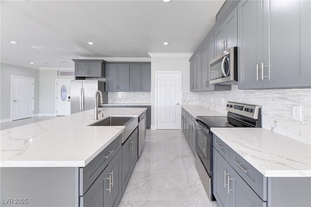 kitchen with a large island, gray cabinets, stainless steel appliances, light stone countertops, and sink