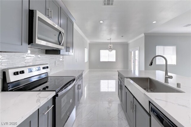 kitchen featuring appliances with stainless steel finishes, gray cabinetry, light stone countertops, and sink