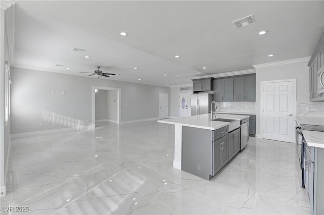 kitchen with a center island with sink, gray cabinets, ornamental molding, and appliances with stainless steel finishes