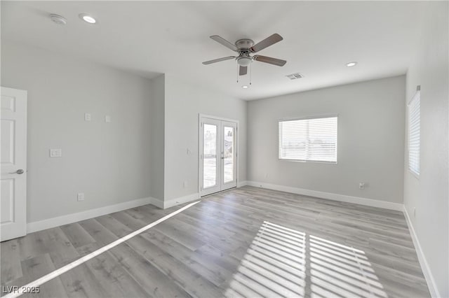 empty room featuring baseboards, visible vents, light wood-style flooring, and french doors