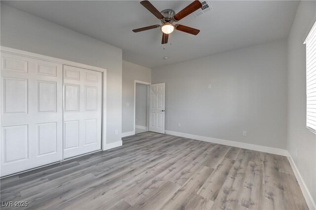 unfurnished bedroom with ceiling fan, light wood-type flooring, and a closet