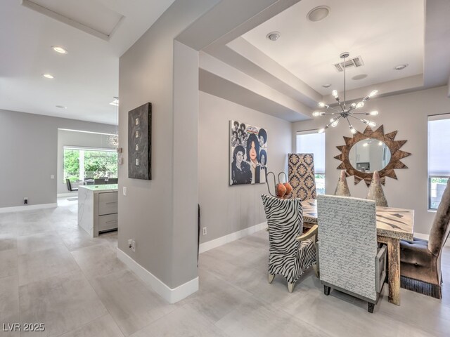 dining area with an inviting chandelier and a raised ceiling