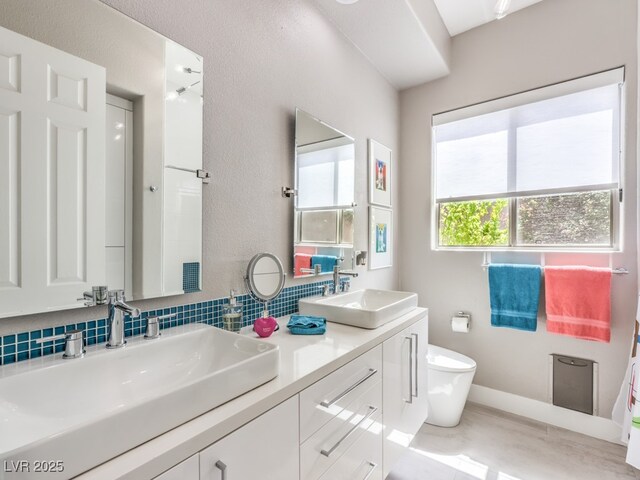 bathroom with decorative backsplash, toilet, and vanity