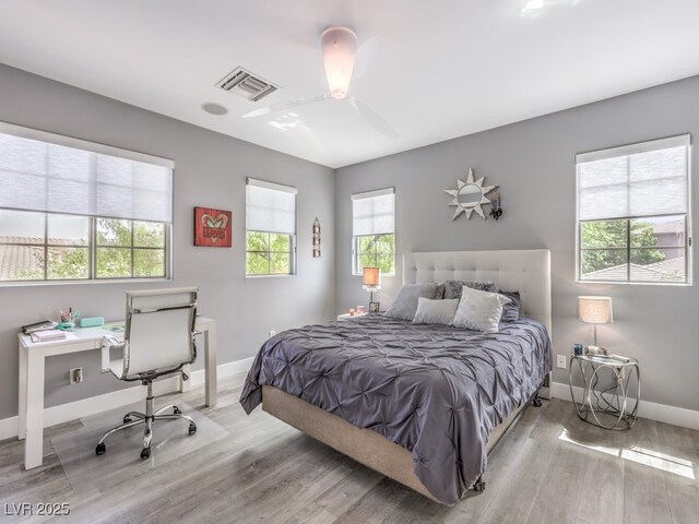 bedroom featuring ceiling fan, light hardwood / wood-style floors, and multiple windows