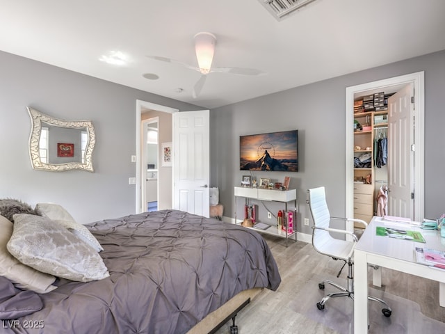 bedroom with ceiling fan, wood-type flooring, a spacious closet, and a closet