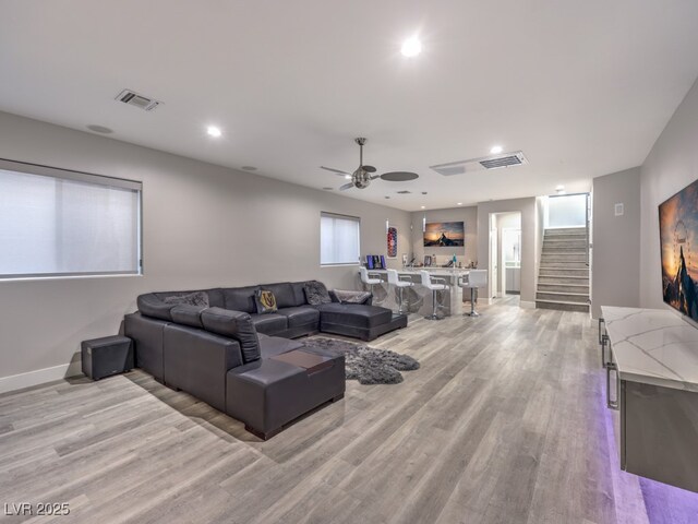 living room featuring ceiling fan, plenty of natural light, and light hardwood / wood-style flooring