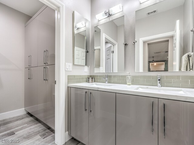 bathroom with wood-type flooring, vanity, and tasteful backsplash