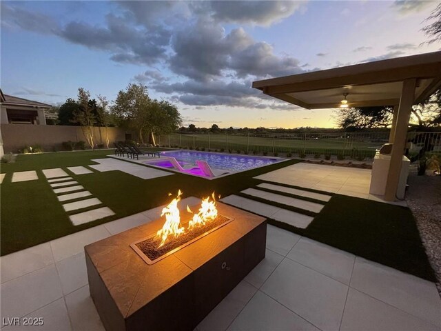 pool at dusk featuring a patio area and a fire pit