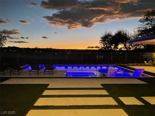 pool at dusk with a patio area