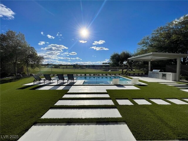 view of swimming pool featuring a patio area, a yard, and an outdoor kitchen