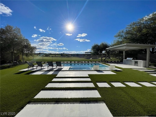 view of swimming pool with a yard, a patio, and an outdoor kitchen